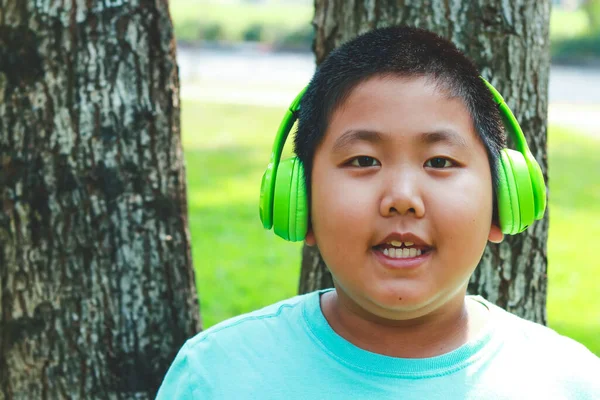 亚洲胖男孩头戴绿色的耳机 站在一棵快乐的树上 儿童学习发展的概念 — 图库照片