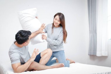 Asyalı çiftler mutlu bir yatak odasında birbirlerine sataşıyorlar. Modern aile kavramı