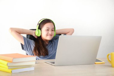 Asyalı kızlar öğretmenlerle iletişim kurmak için bir dizüstü bilgisayar kullanarak evden video aramasıyla çevrimiçi çalışırlar. Koronavirüsün yayılmasını azaltmak için eğitici kavram, sosyal uzaklık (COVID-19)