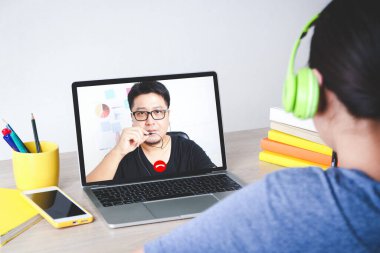 Asyalı kızlar evlerinden bilgisayar aracılığıyla video arama uygulaması ile öğreniyorlar. Sosyal uzaklık kavramı, eğitim için teknoloji kullanımı