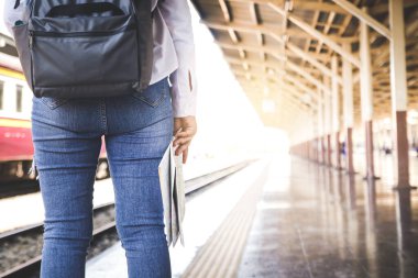 Trenle seyahat eden turistler, seyahat güzergahını incelemek için ellerinde kağıt bir harita tutuyorlar.