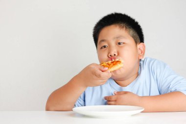 Şişman çocuklar mutlu bir şekilde pizza yerler. Büyük miktarlarda yendiğinde, vücut yağı sağlıklı değildir..