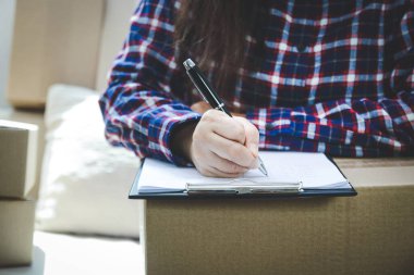 Malları postayla müşteriye teslim ederek internet üzerinden iş yapan genç kadınlar, bilgileri kaydediyor.