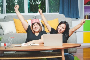 İki Asyalı kadın internet üzerinden iş yapan girişimciler. Ellerinizi kaldırın, ürün satmaktan mutluluk duyarız.