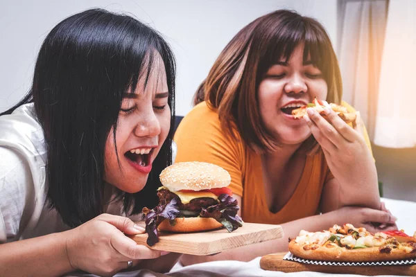 Två Feta Tjejer Äter Pizza Och Hamburgare Sängen Sovrummet Lycklig — Stockfoto