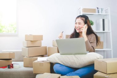 İnternette iş yapan genç girişimci siparişleri kontrol ediyor ve paketi hazırlıyor. Modern iş kavramları