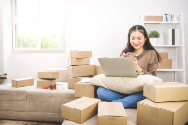 İnternette iş yapan genç girişimci siparişleri kontrol ediyor ve paketi hazırlıyor. Modern iş kavramları