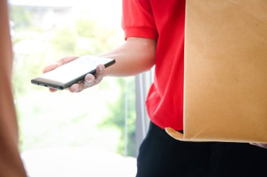 Bir adam internetten müşteriye teslimat yapar ve imzalaması için akıllı telefon gönderir. Yeni normal kavram, sosyal uzaklık