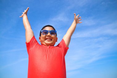 Kırmızı gömlek giyen çocuk iki elini kaldırdı. Mutlu deniz oyunları