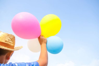 Erkekler balon tutuyor, tatilde mutlu oynuyorlar Arka plan parlak gökyüzü.