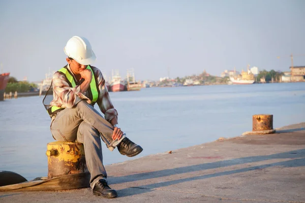 The male engineer wore a white safety hat at the pier. He had stress.