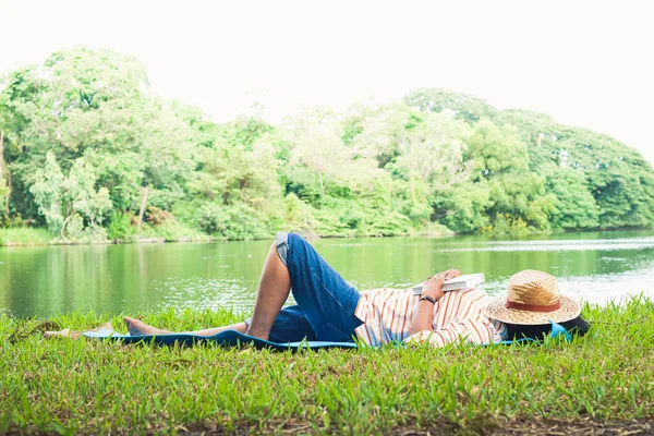 An elderly woman slept reading until sleeping in a park with a large pond. Happy, simple life in retirement. Senior community concept