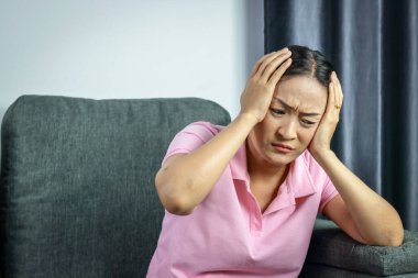 Asyalı bir kadın ellerini başına koydu ve kendini stresli ve endişeli hissetti. Depresyona girmek hemen bir doktora görünmeli. Sağlık hizmeti kavramı