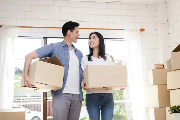 Asian couple buy a new house, hold a paper box to put things in. Move into a new house. Concept of starting a new life, creating a family. copy space