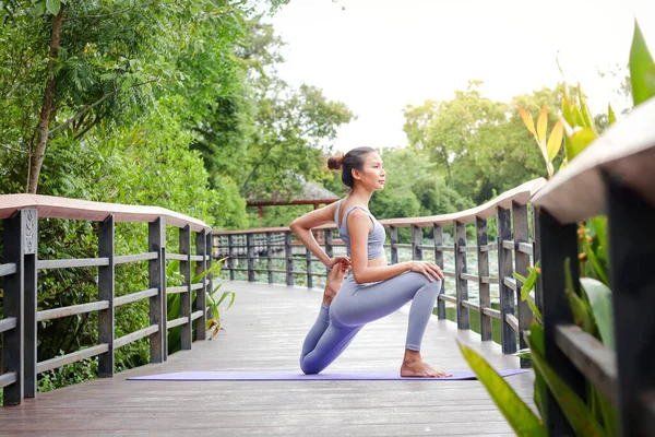 Sağlıklı genç Asyalı kadın sabahları açık hava parkında yoga egzersizi için oturur. Boşluğu kopyala
