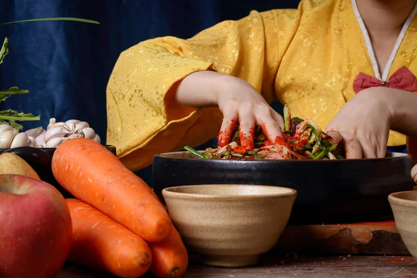 Asian women wearing hanbok, a Korean national costume, cook traditional kimchi, fermented cooking. Scented Including carrot, white cabbage, onion, cayenne pepper, garlic, salt, radish, apples — Stock Image Asian Women Wearing Hanbok Korean National Costume Cook Traditional Kimchi Stock Photo
