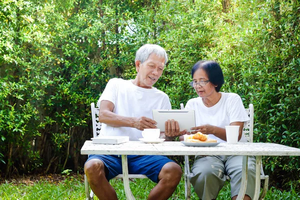 Casal Idosos Asiáticos Sentados Jardim Manhã Veja Notícias Tablet Juntos — Fotografia de Stock