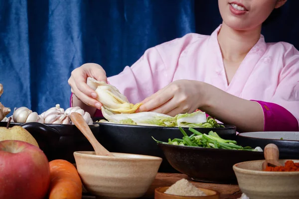 Korean women wearing traditional pink hanboks doing kimchi She is mixing the ingredients in the bowl. To taste delicious. The concept of charming fermented cooking And fragrant, Asian food — Stock Image Korean Women Wearing Traditional Pink Hanboks Doing Kimchi She Mixing Stock Picture