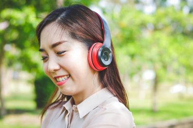 Ofiste çalışan güzel bir kız kulaklık takıyor, gülümsüyor.