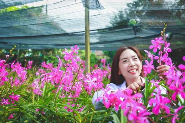 Kız beyaz bir araştırmacı üniforması giyiyordu. Orkide bahçesindeki kağıt üzerine bilgi kaydetmek için ayağa kalkın