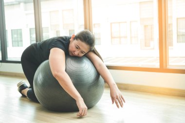 Şişman Asyalı kadınlar spor yaparken yorulurlar. Yoga topuna sarılarak uyu.