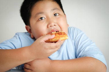 Şişko çocuk çok kilo almış, pizza yiyor.