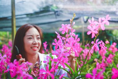 Kız beyaz bir araştırmacı üniforması giyiyordu. Orkide bahçesindeki kağıt üzerine bilgi kaydetmek için ayağa kalkın