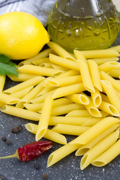 pile of raw pasta (penne) raw on a cutting board