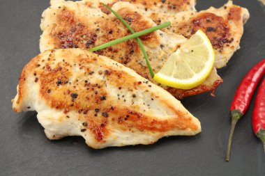 Siyah arka planda pişirilmiş tavuk filetosu.