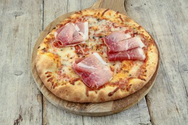 Ahşap arka planda kuru jambonlu pizza.