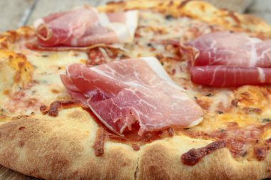 Ahşap arka planda kuru jambonlu pizza.