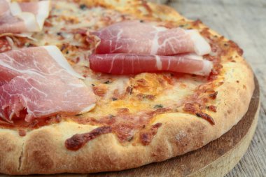 Ahşap arka planda kuru jambonlu pizza.