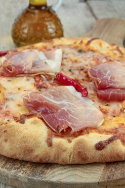 Ahşap arka planda kuru jambonlu pizza.