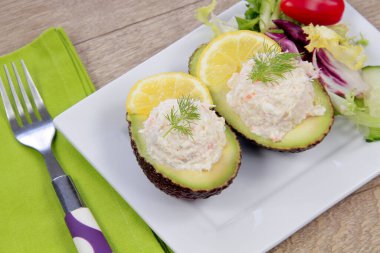 Tabağında surimi olan yarım avokado.