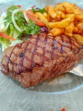Lezzetli ızgara biftek, patates ve salata..