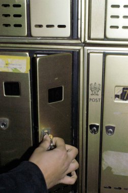 Postalarını almak için posta kutusunu anahtarla açan kişi