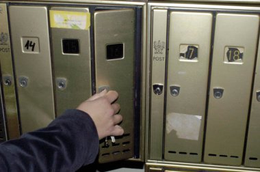 Postalarını almak için posta kutusunu anahtarla açan kişi