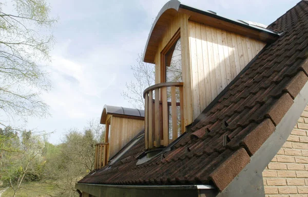 House with a wooden balcony, on the roof, green leaves