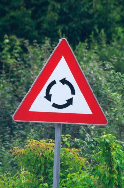 Kırmızı üçgen kavis işareti ve arkasında yeşil çayır olan siyah yönlü oklar.