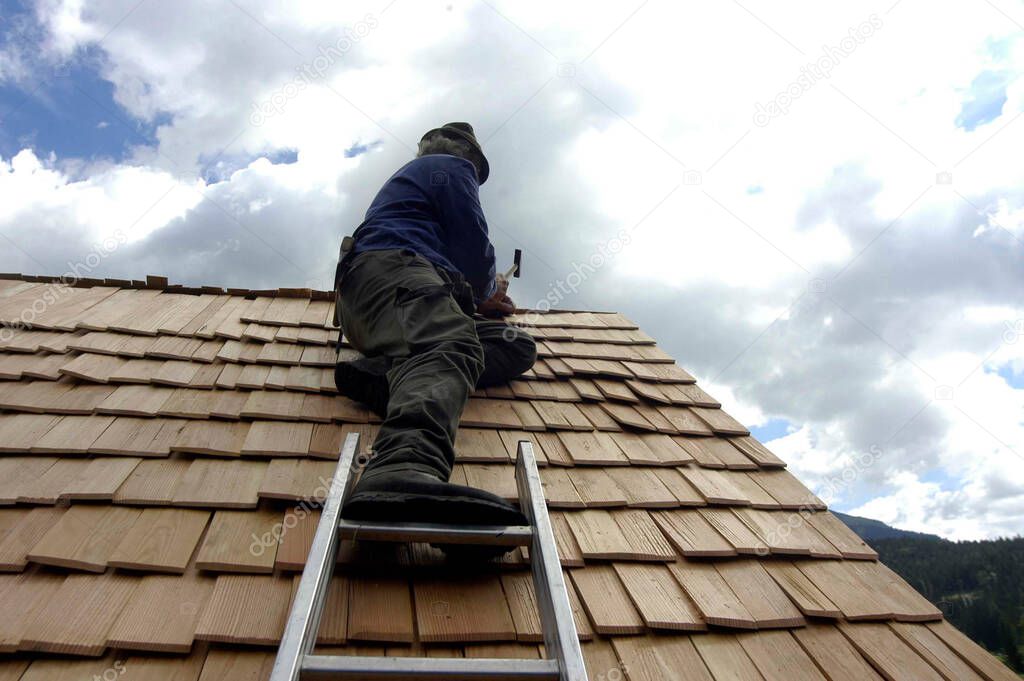 farmer repairing the roof on his house, roof shingles on a building