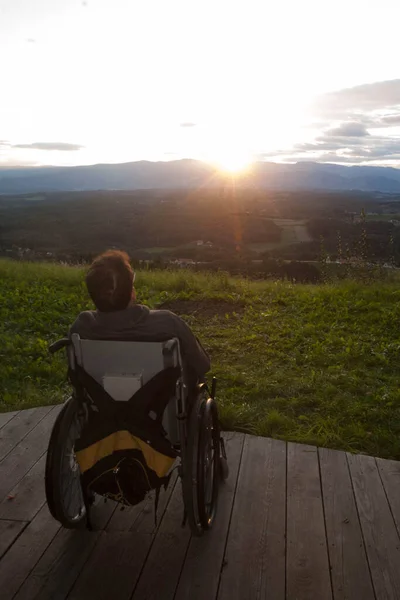 person in a wheelchair on a porch at sunset, accessibility