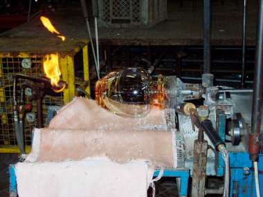 İş yerinde cam üfleyici, ısı ve camla çalışıyor.