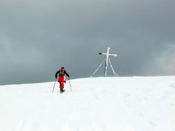 ski tour in the mountains, reaching summit cross at a gray and cloudy day