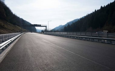 Bir otobanda asfalt yol, tepe manzarası ve ağaçlar bir yana