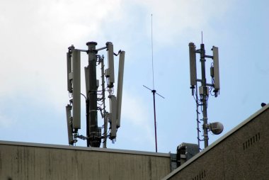 bir binanın tepesindeki mobil ağ antenleri, mavi gökyüzü