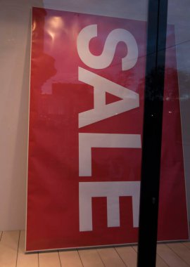 Alışveriş penceresinde indirim tabelası, kırmızı arka plan, beyaz harfler.