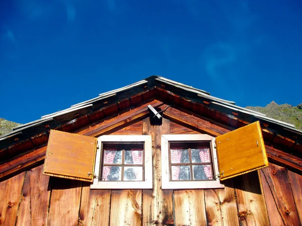 木の家の屋根の下の木製の窓澄んだ青い空 — ストック写真