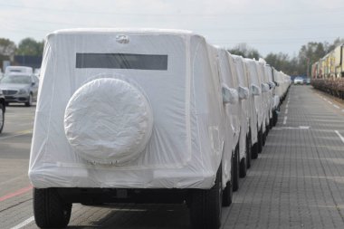 Bir sıra off road aracı beyaz bir muşambayla kaplanmış.