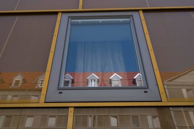 Şehirdeki modern bir binanın minimalist cam cephe tasarımı diğer taraftaki binayı yansıtıyor.