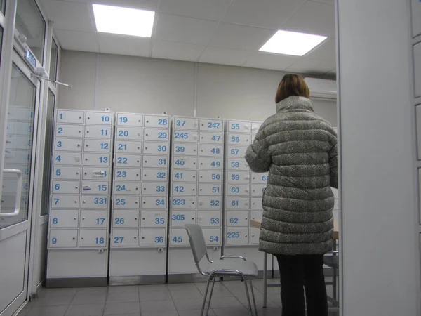 person standing in room with safe deposit boxes or safe deposit lockers, blue numbers on gray boxes